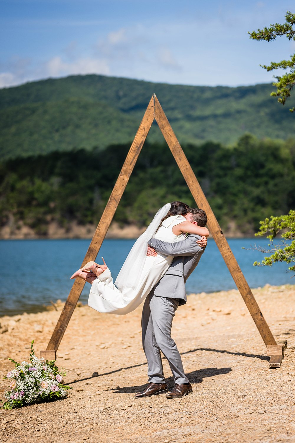 A marrier hugs their partner and hoists her up in the air in a bout of excitement after their first kiss during their Virginia elopement at Carvin’s Cove.