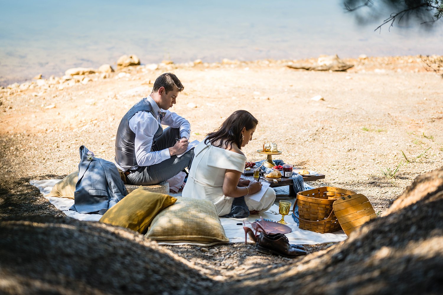 A bride and groom sit along the shore of Carvin’s Cove having a brunch picnic and writing their vows during their elopement.