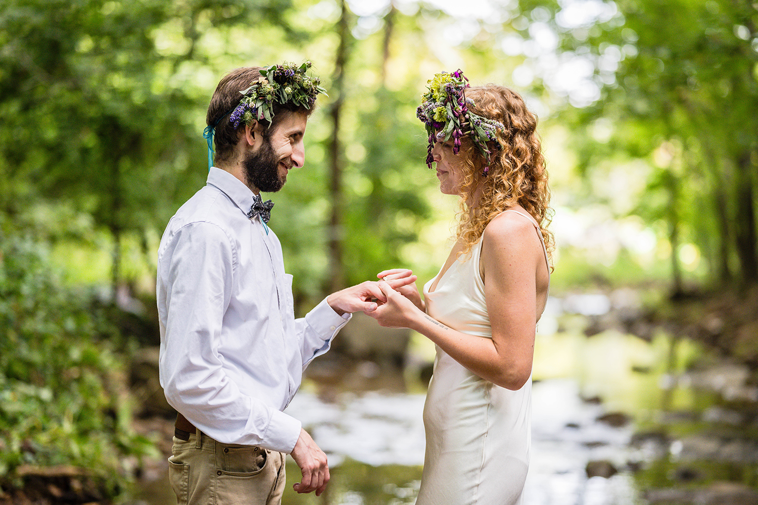 A couple on their elopement day stand in a creek and exchange rings.