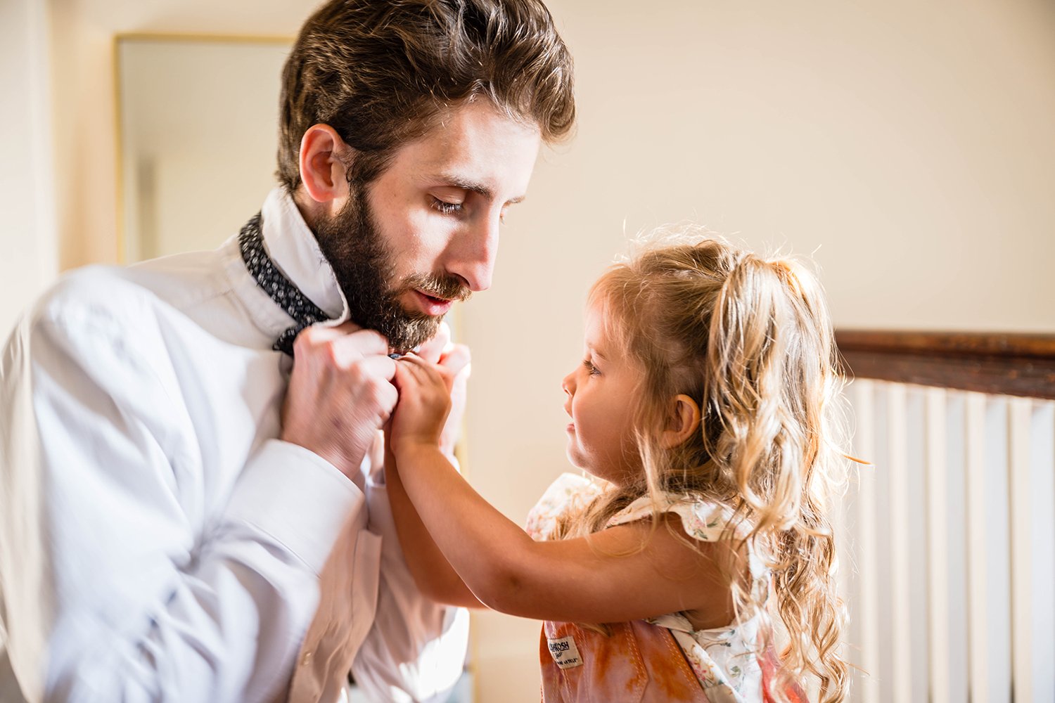A small child helps her parent put on a bowtie ahead of their elopement day at Fishburn Park.
