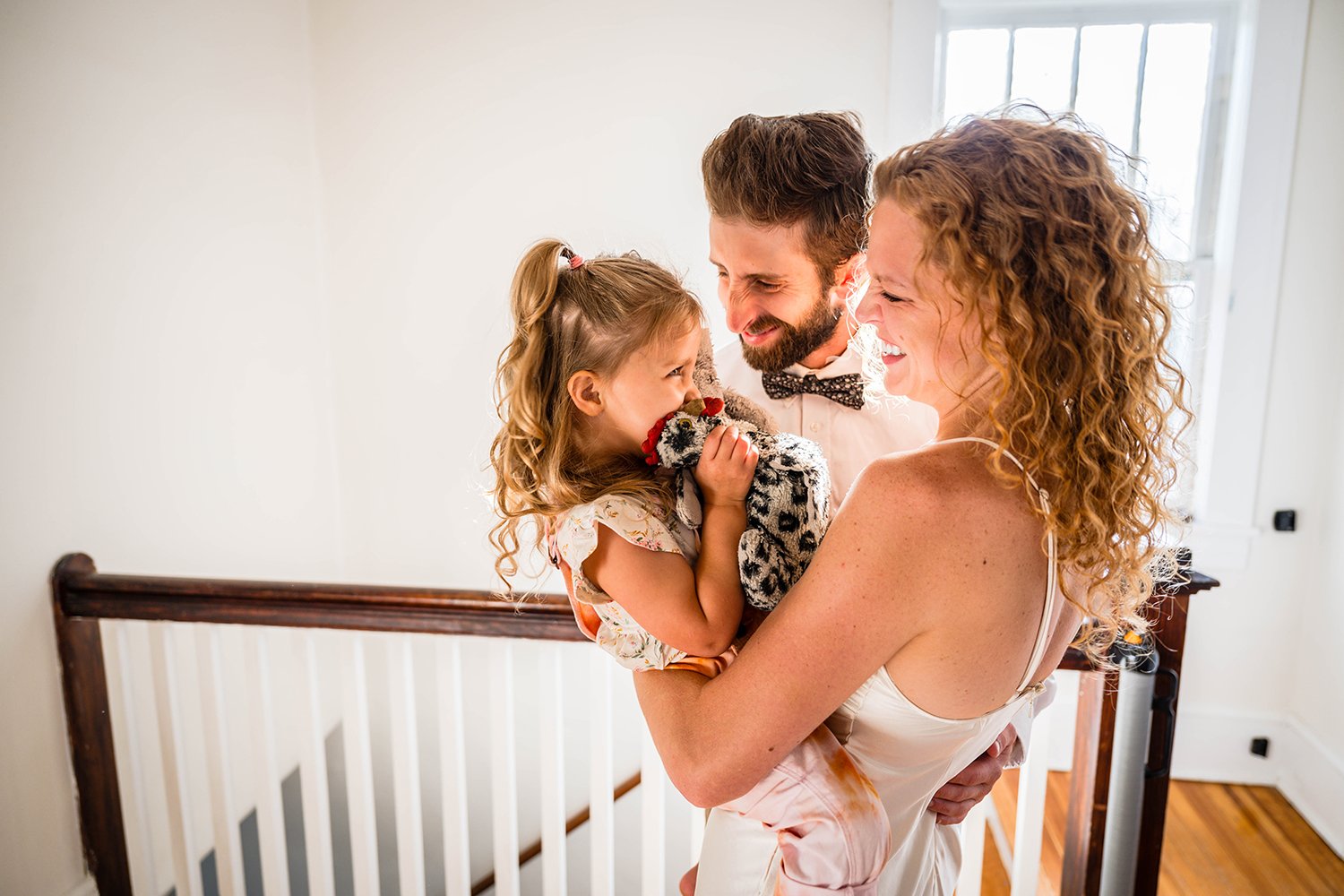 A family of three come together for a group hug and smile and laugh at one another.