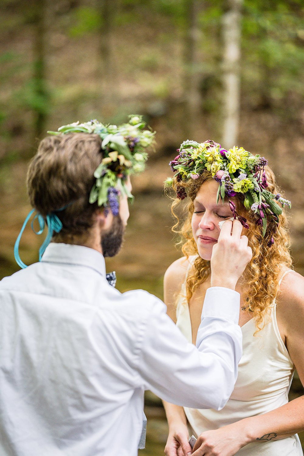 A bride sheds a tear and a groom pats her cheek with a tissue during their elopement ceremony at Fishburn Park in Roanoke, Virginia.