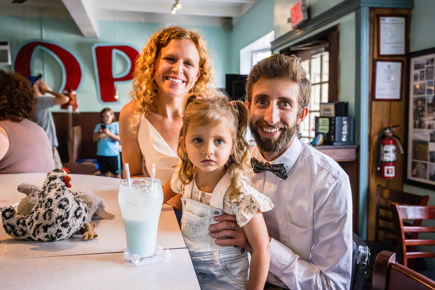 A family of three smiles for a photo inside of Pop's Ice Cream &amp; Soda Bar in Grandin Village in Roanoke, Virginia.