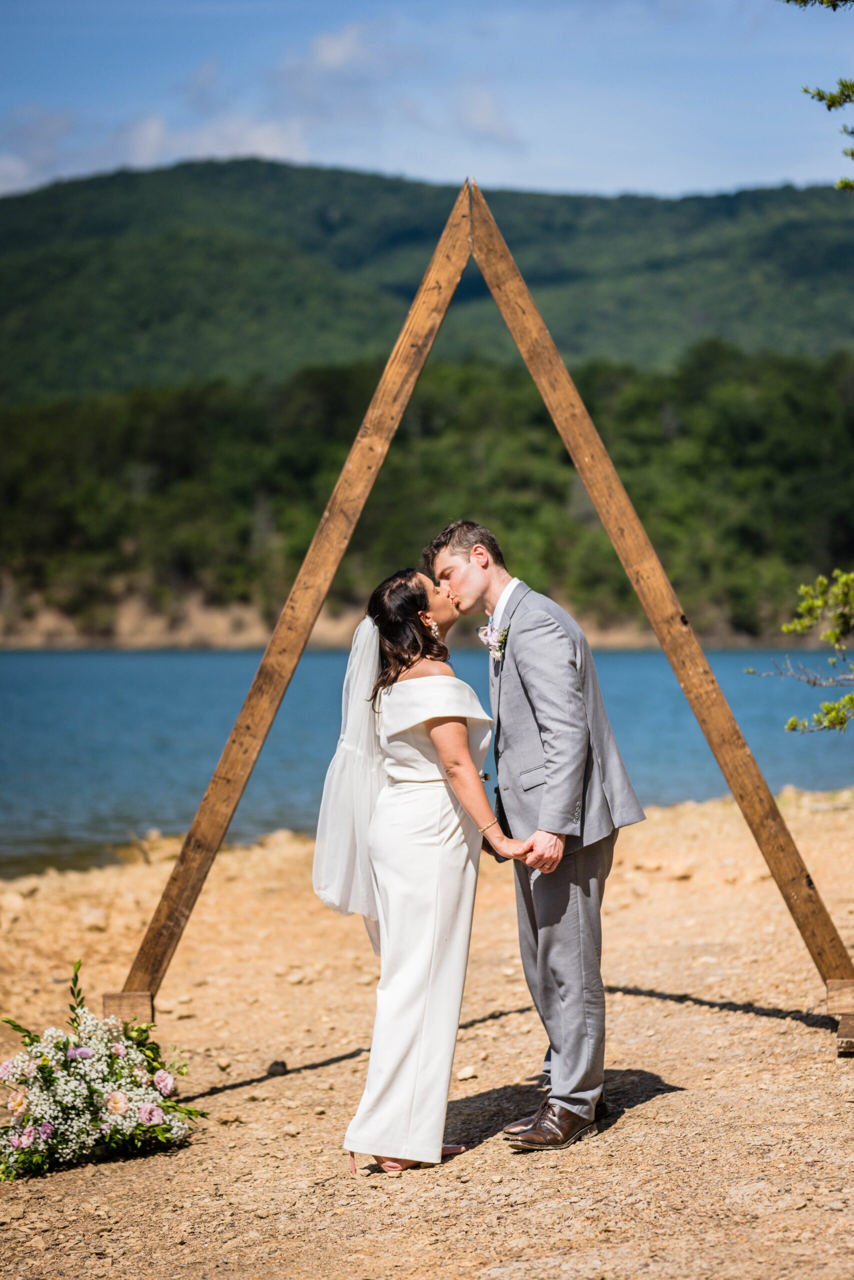 A wedding couple kisses under a ceremony arch during their Virginia elopement at Carvin's Cove.