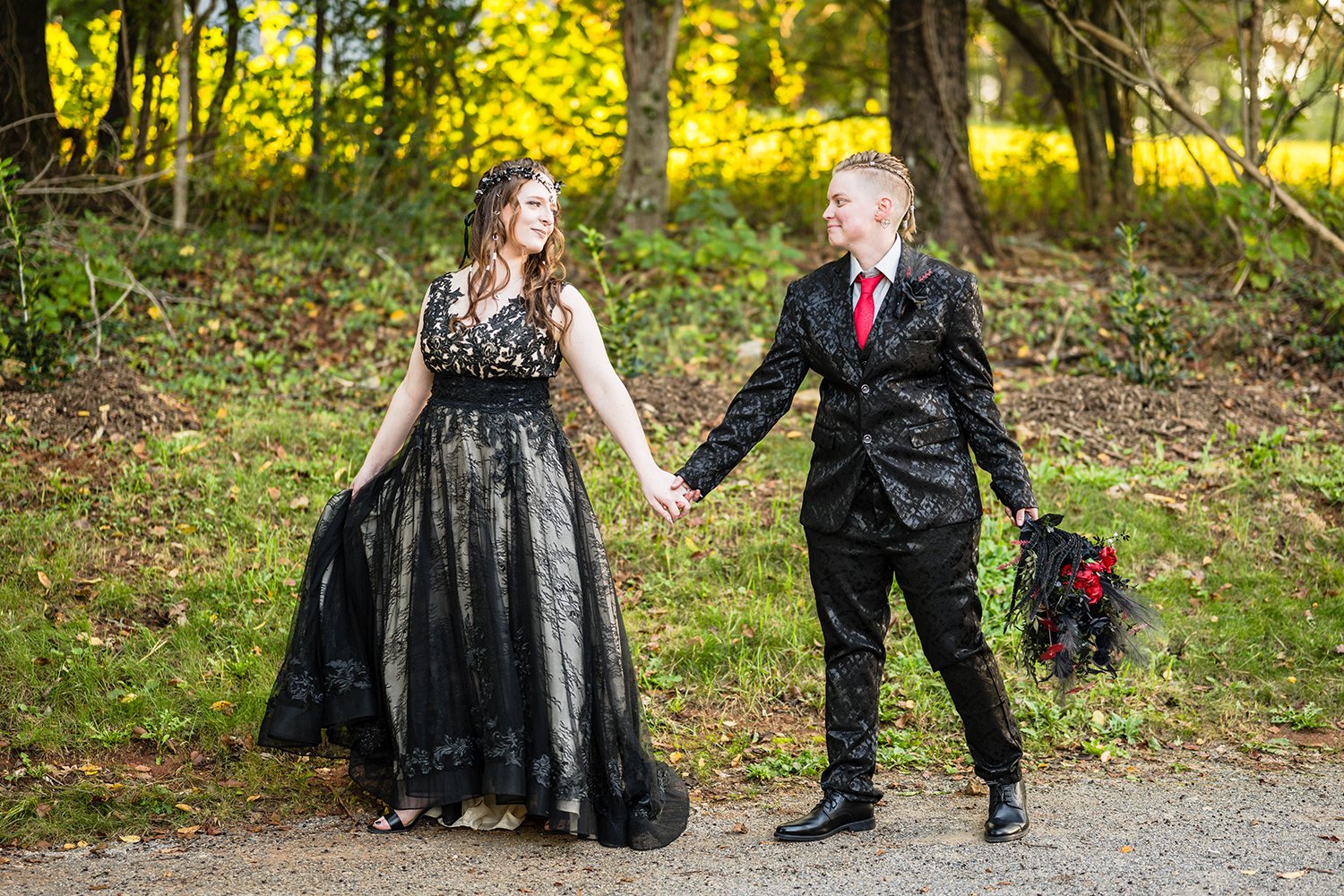 A lesbian wedding couple both dressed in black walk hand in hand together outside of their Airbnb during their elopement in Roanoke, Virginia.