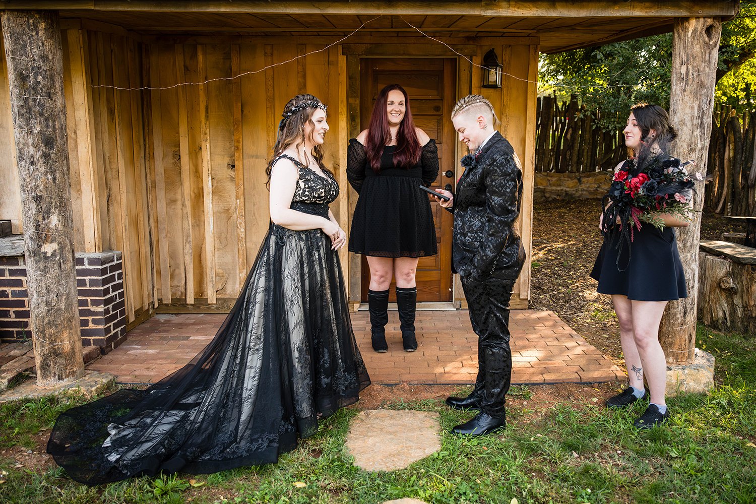 An LGBTQ+ couple stand in the yard of a Roanoke Airbnb reading their vows while one person stands on the porch waiting and another person holds the bouquet.