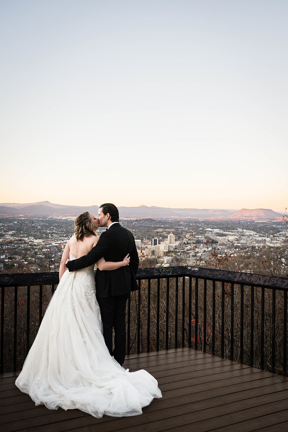 A couple on their elopement day go in for another kiss at the Mill Mountain Star, which gives a panorama view of Downtown Roanoke and the Blue Ridge Mountains. 