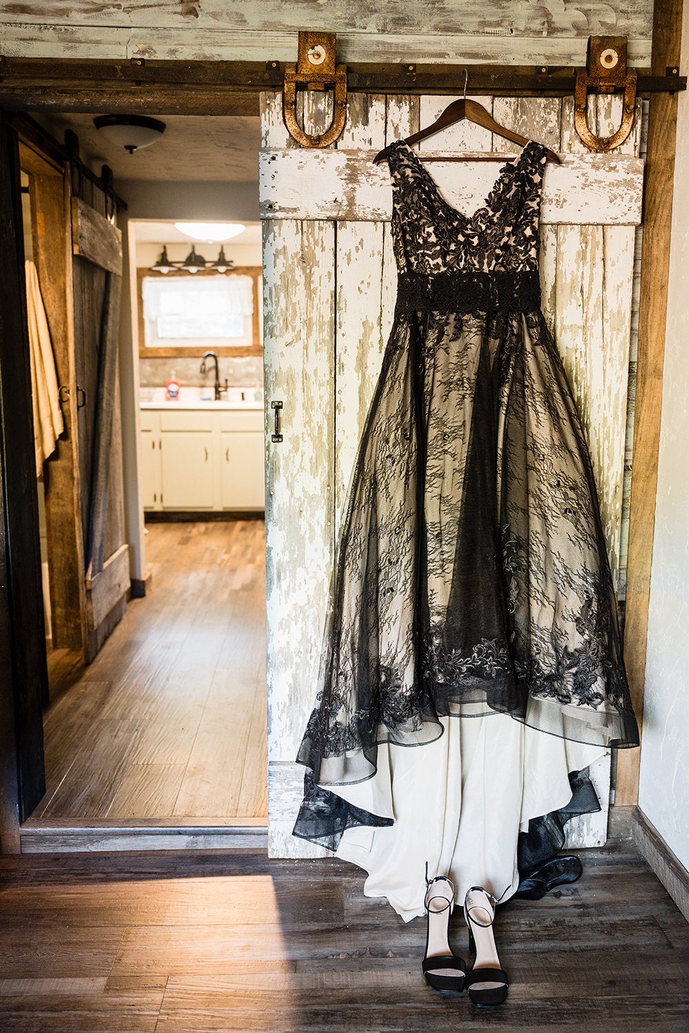 A black wedding dress hangs from a rustic sliding door inside.