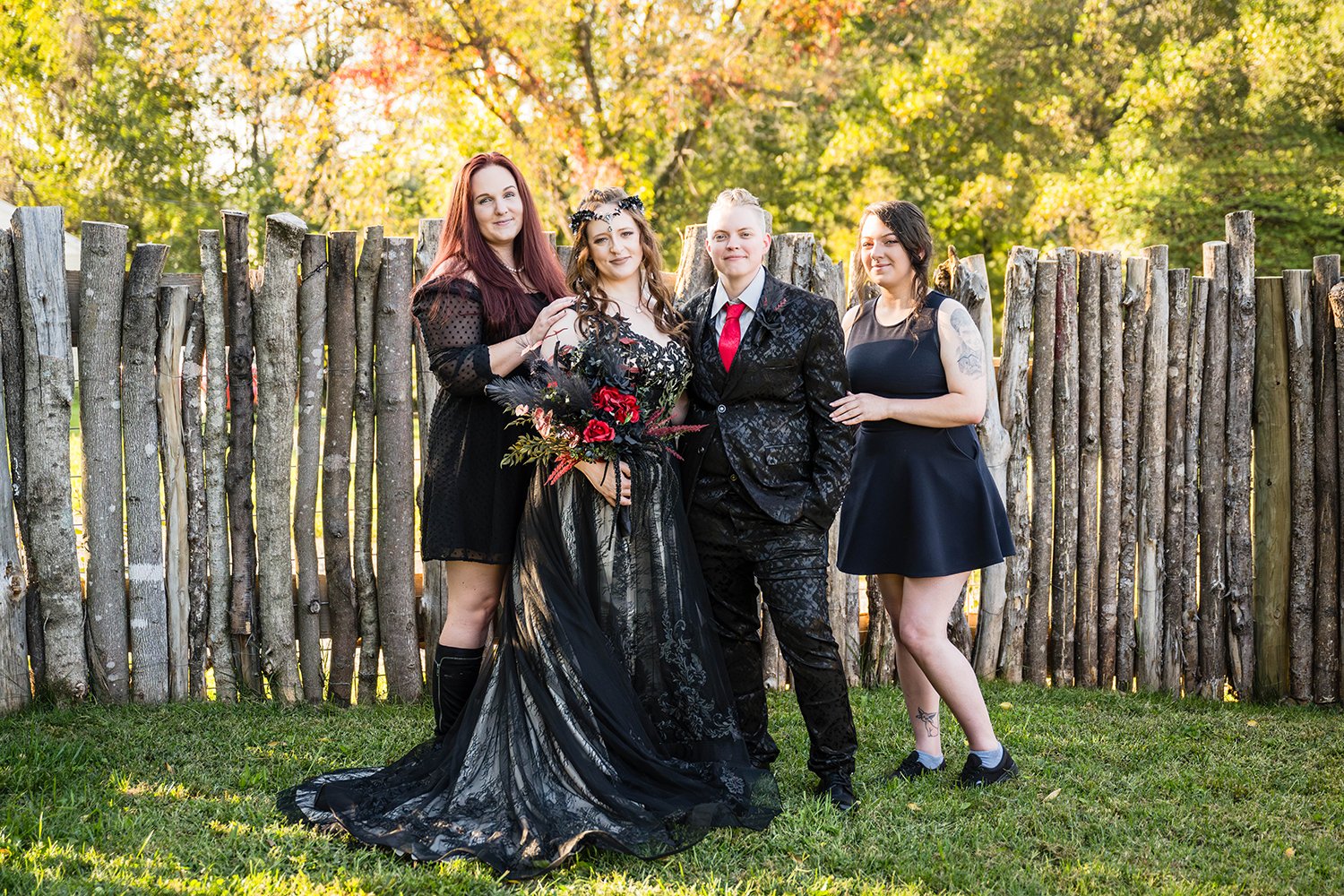 A newlywed couple dressed in black stand outside in the backyard of their Airbnb with their wedding party for a photo.