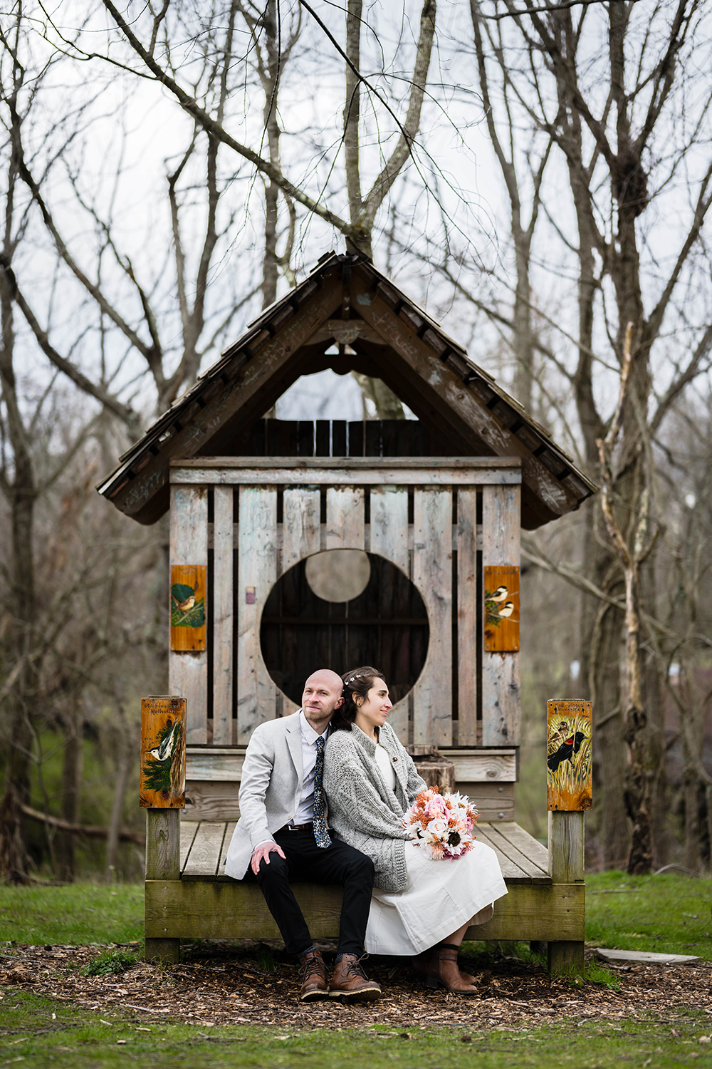 A couple sit together on a structure shaped like an over-sized birdhouse at Heritage Park.