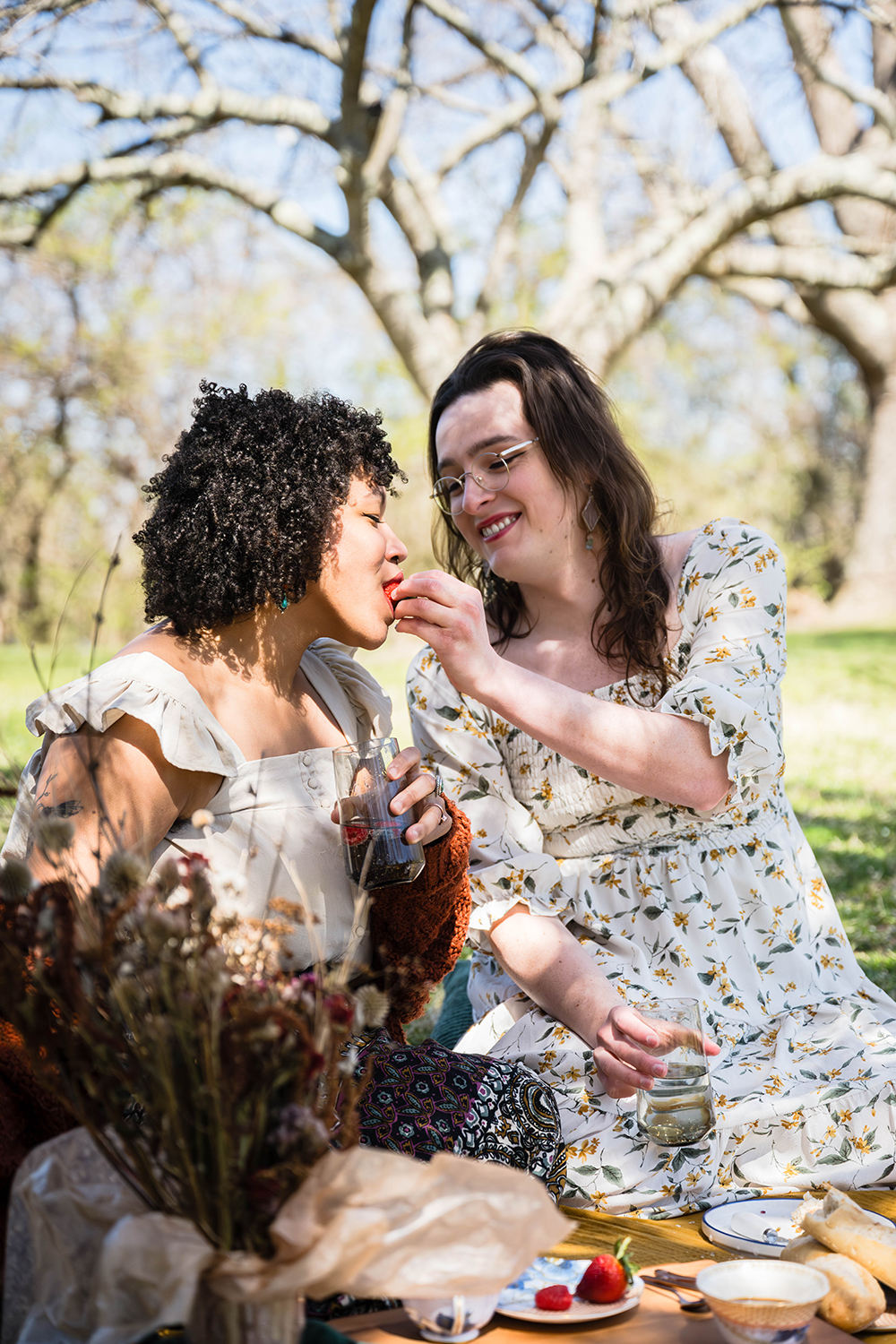 A partner in a couple feeds their significant other a strawberry while having a picnic at Duck Pond for their elopement.