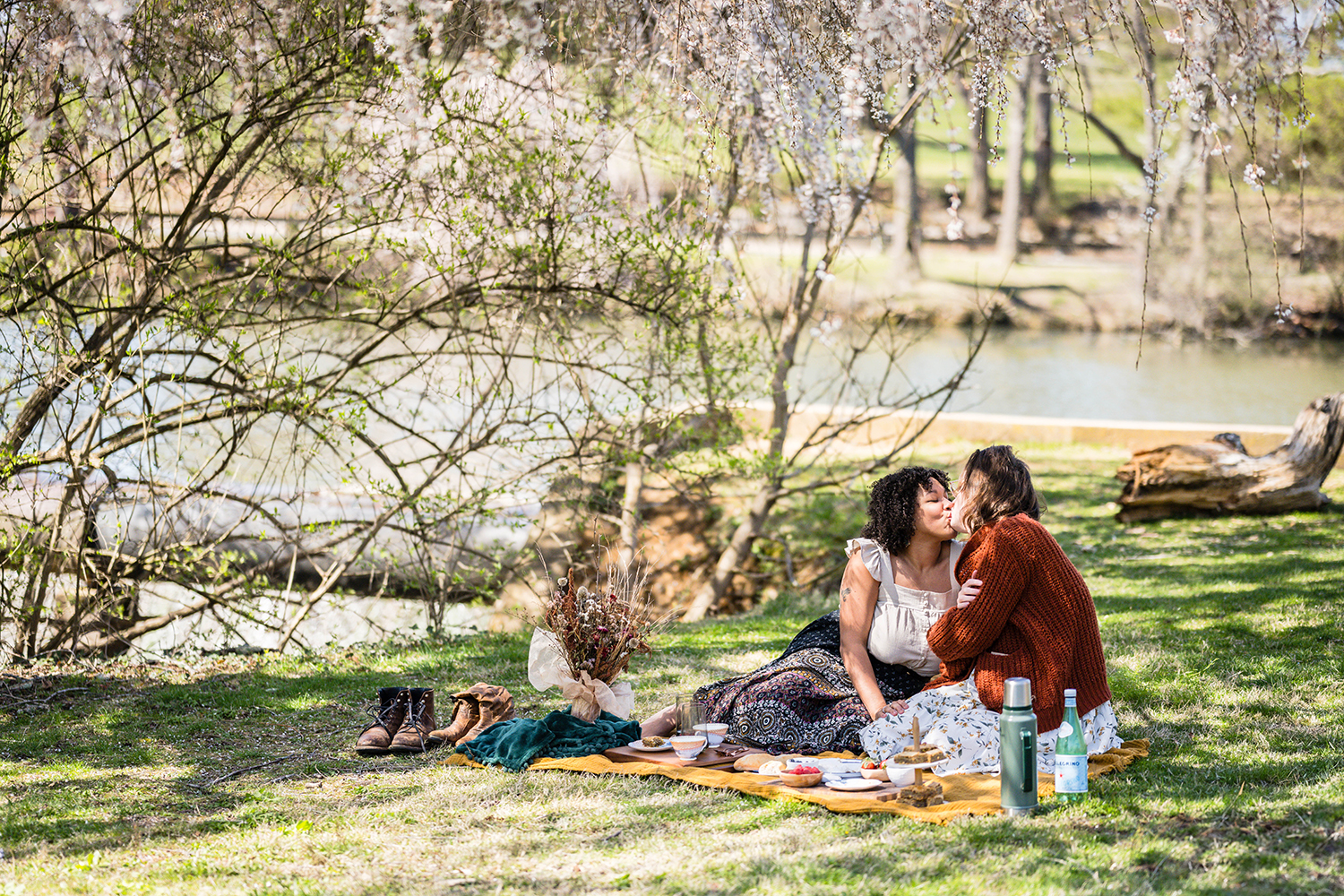 A queer couple has a picnic at Duck Pond and share a kiss under the shade.