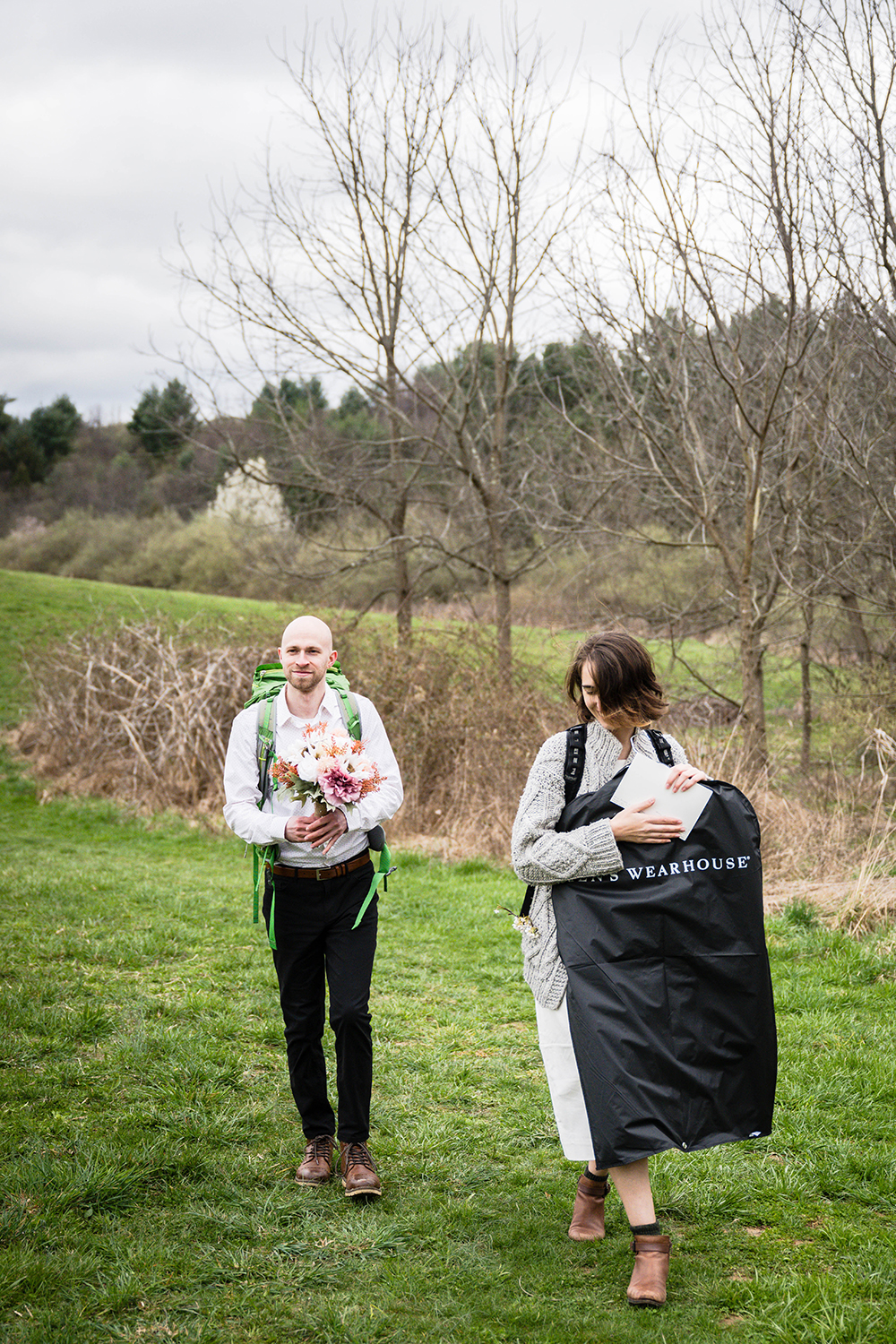 A couple walk together holding various items they need for their ceremony on their elopement day at Heritage Park.