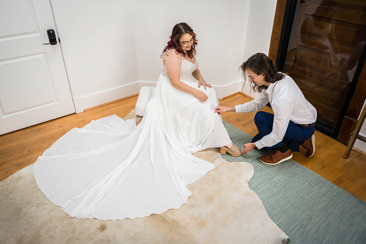 A couple on their elopement day help each other get ready for their wedding day in their hotel room at Fire Station One in Roanoke, Virginia.