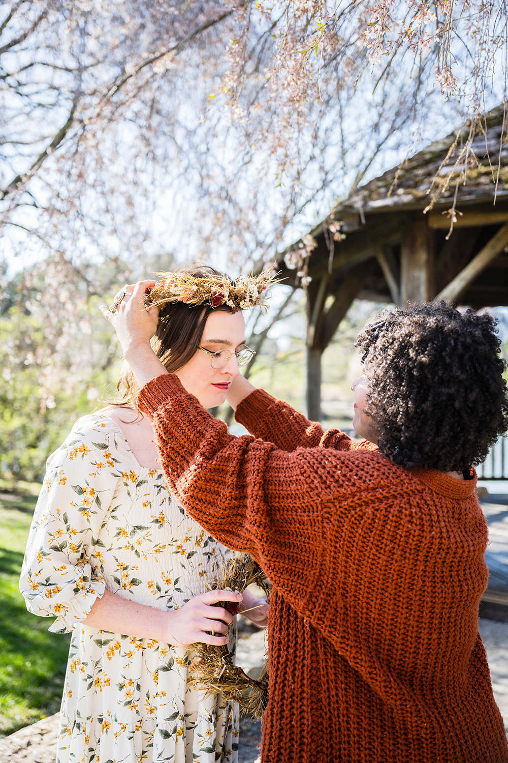 A couple helps one another put on their dried flower crowns before their elopement ceremony at Duck Pond.