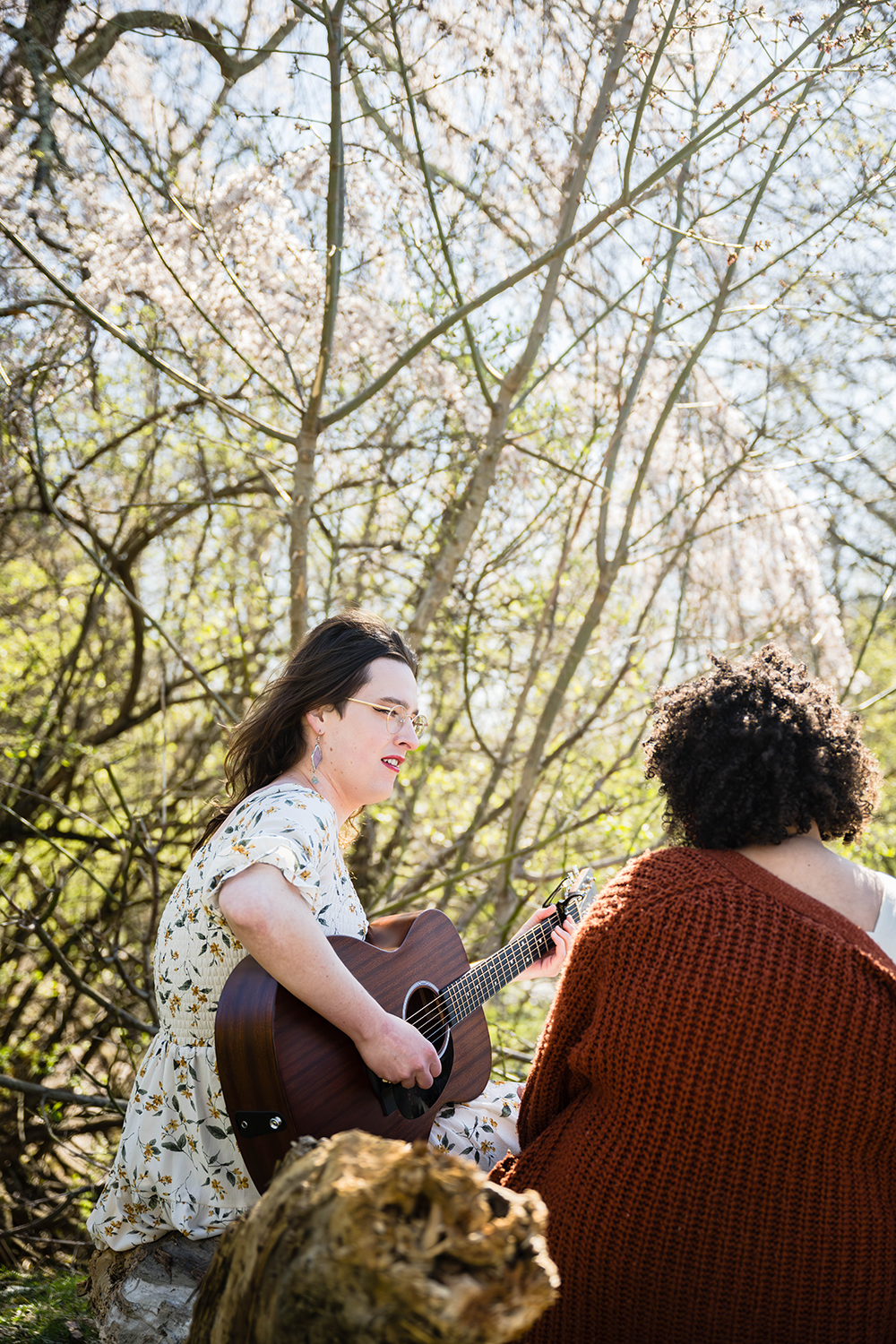 A woman plays the guitar for her partner on their elopement day at Duck Pond.