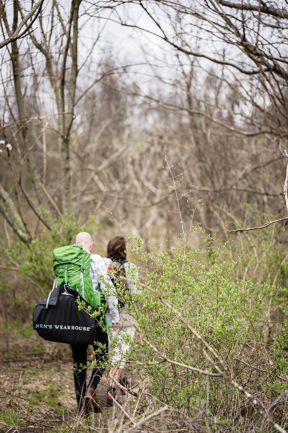 Two marriers wearing hiking backpacks walk into a forested area along a trail on the Appalachian Trail in Virginia.