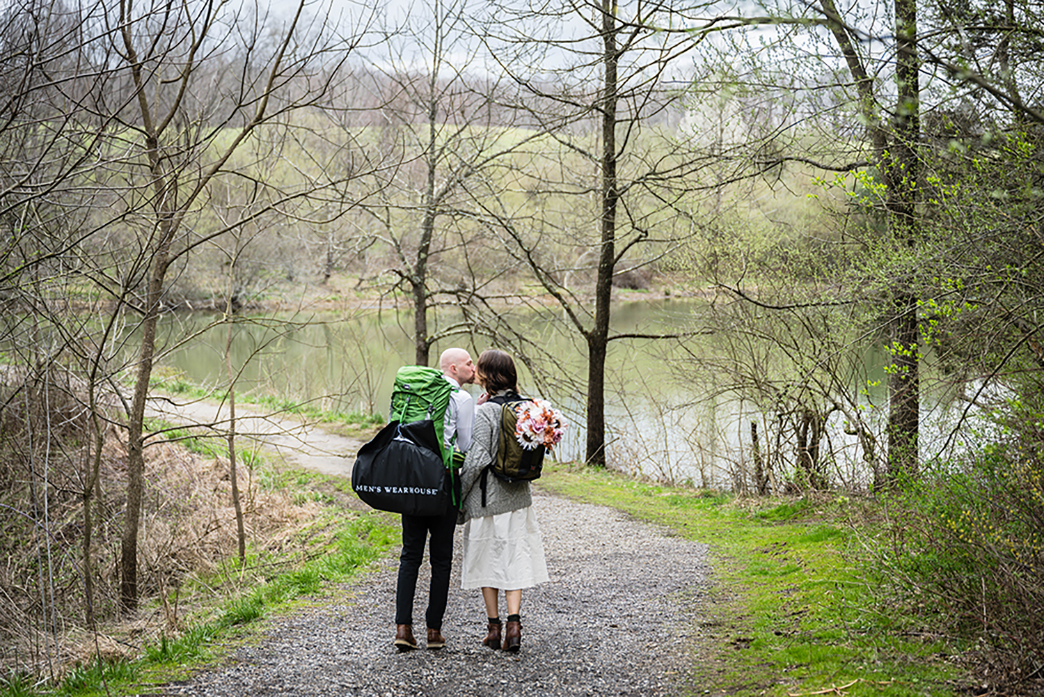 A couple wearing backpacks go in for a kiss while hiking on the Appalachian Trail in Virginia for their elopement.