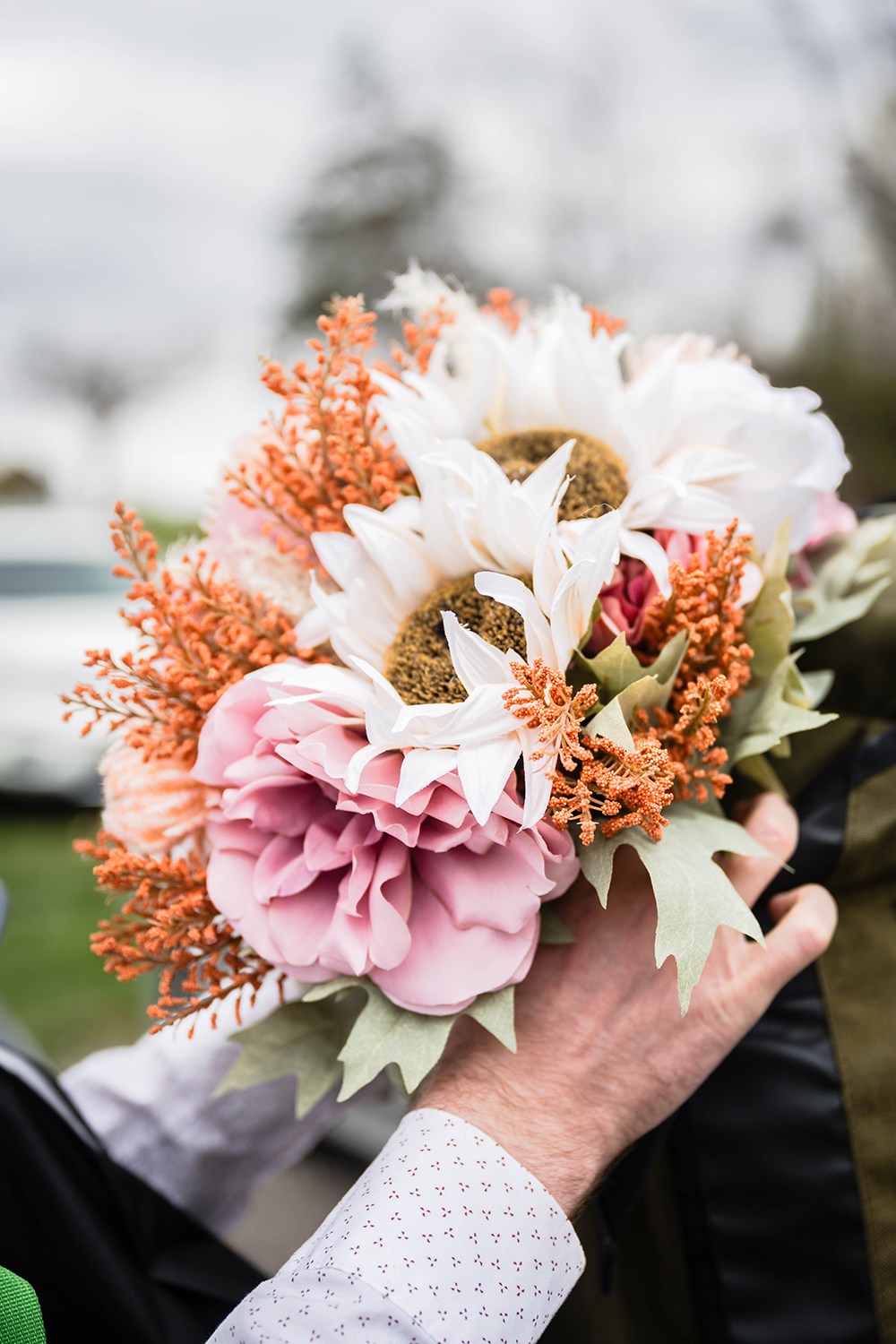 A marrier secures a wedding bouquet into the front pocket of his partner's backpack before embarking on their hiking elopement on the Appalachian Trail in Virginia.