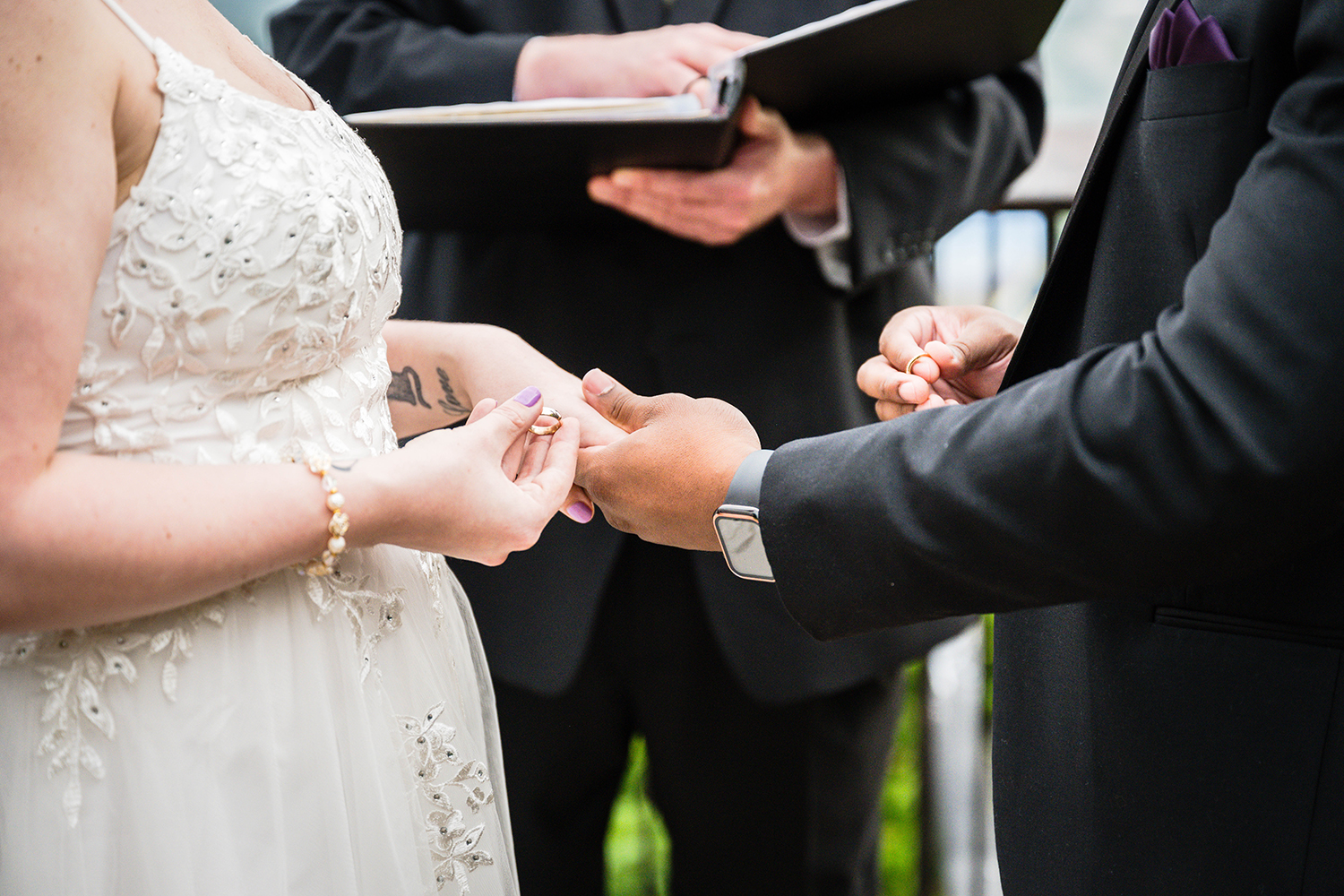 A couple on their wedding day stands in front of their officiant and holds their wedding rings waiting for the officiant to begin their ring exchange during their ceremony at Mill Mountain Park.