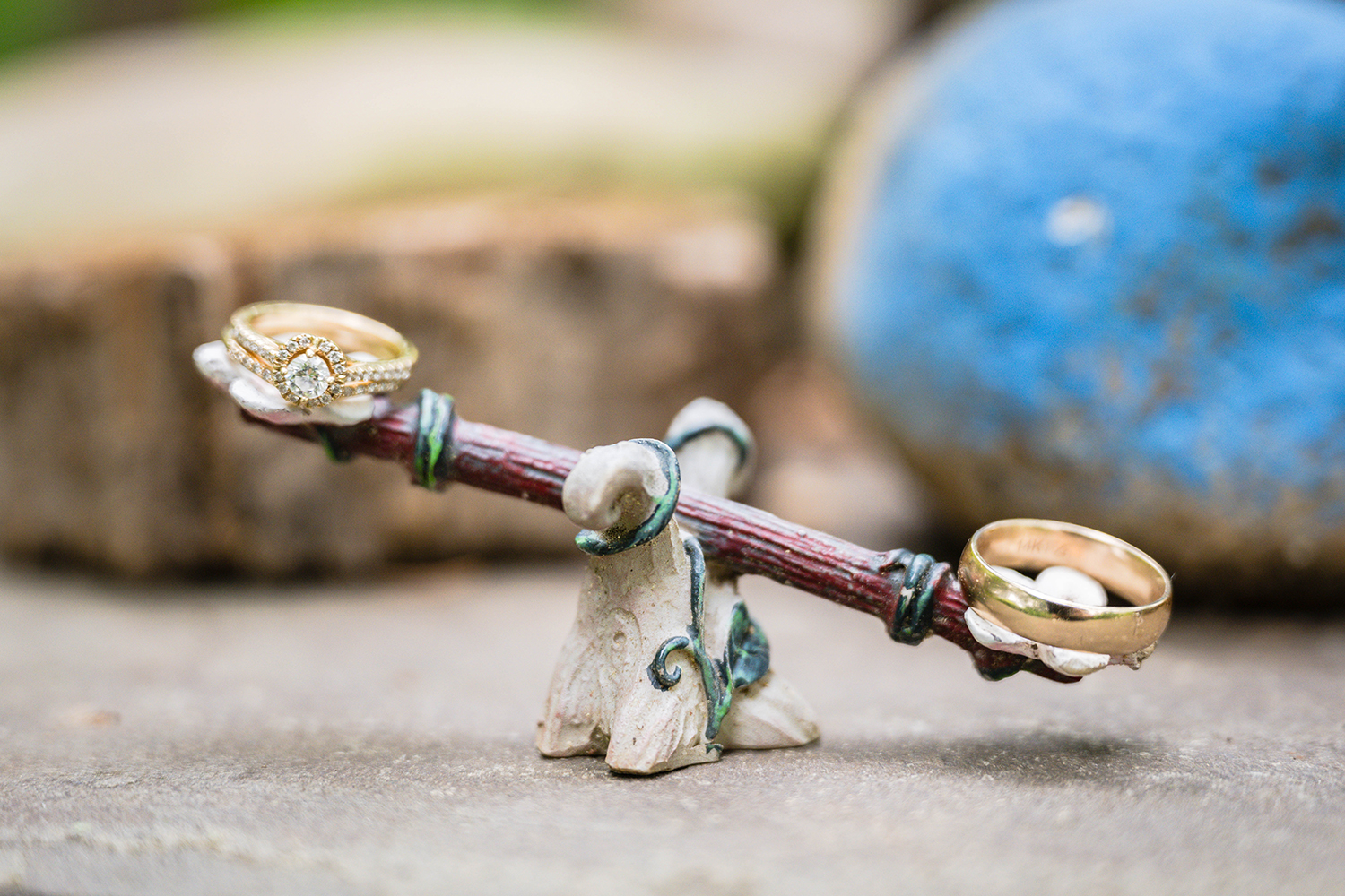 Two wedding rings are placed on a miniature toy seesaw.