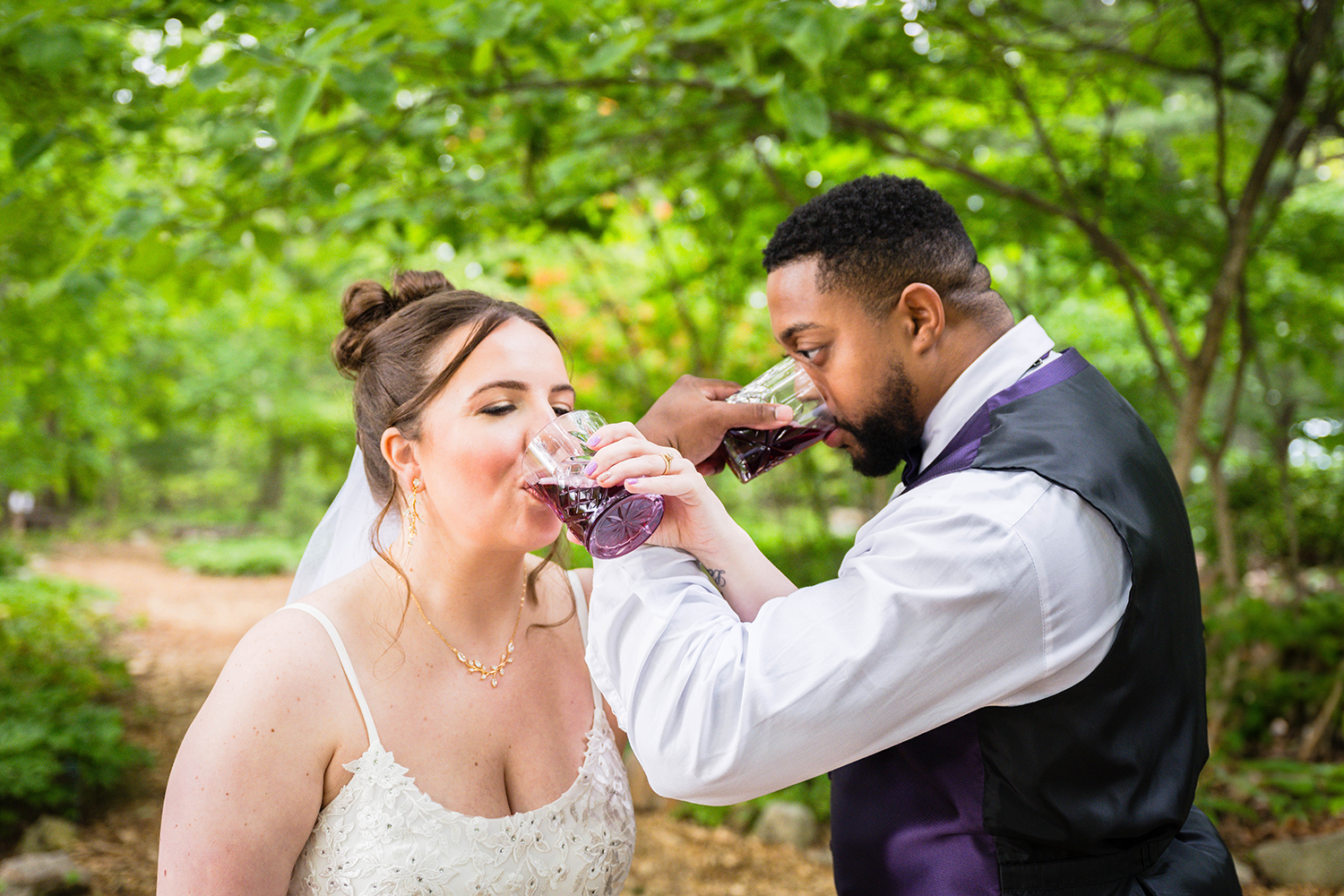 A couple intertwines arms and drinks out of their respective glasses on their wedding day.