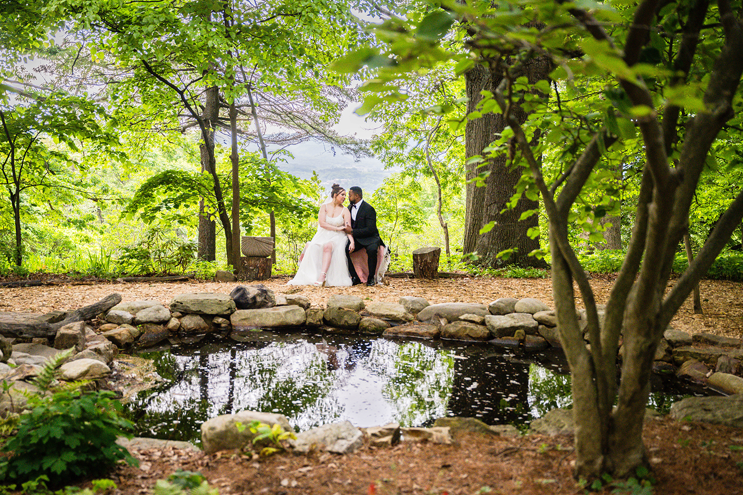 A couple on their elopement day sits in the Mill Mountain Wildflower Garden with their picnic basket to the side.