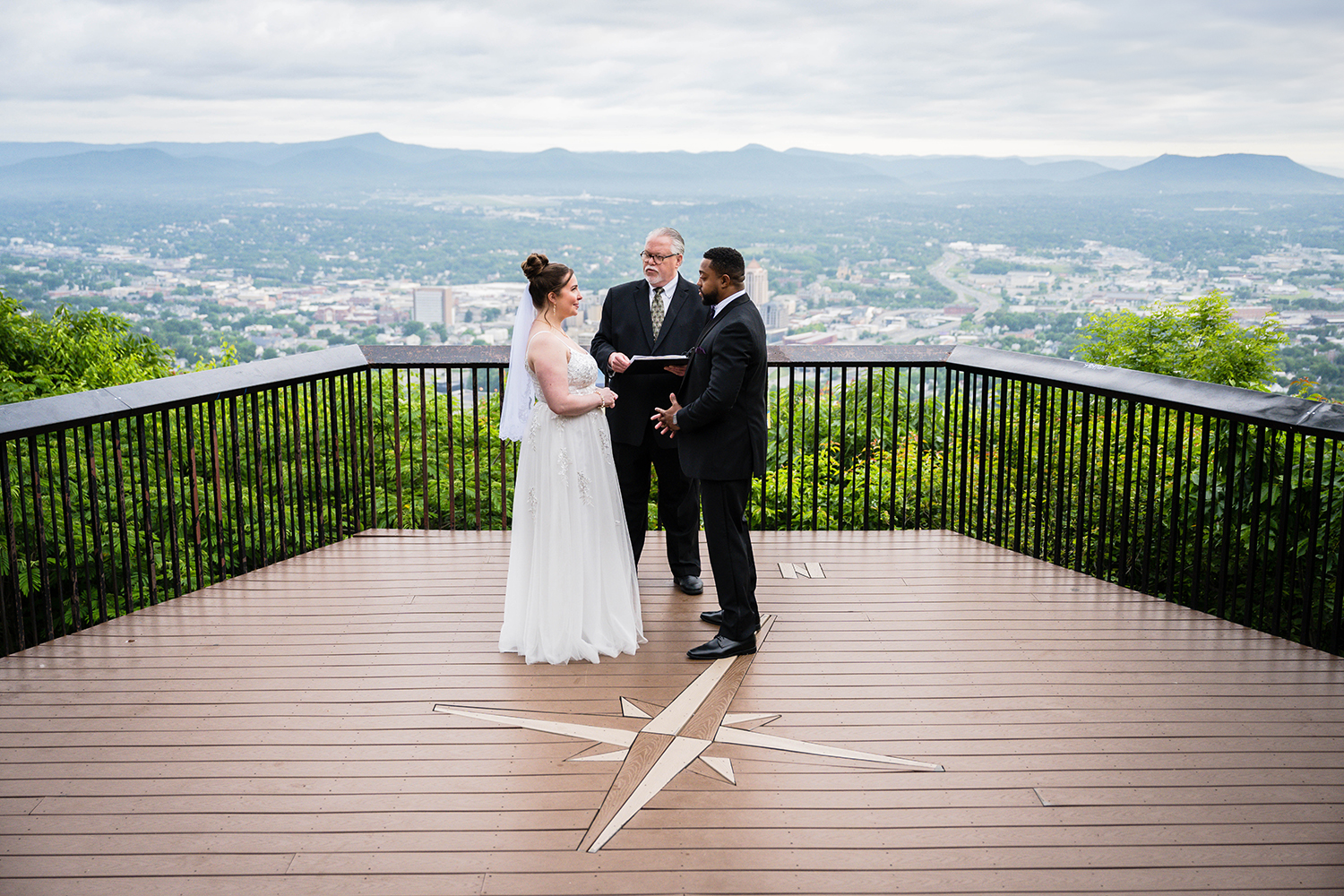 A couple stands with their officiant at Mill Mountain Overlook to get married on their elopement day on the Blue Ridge Parkway in Virginia.