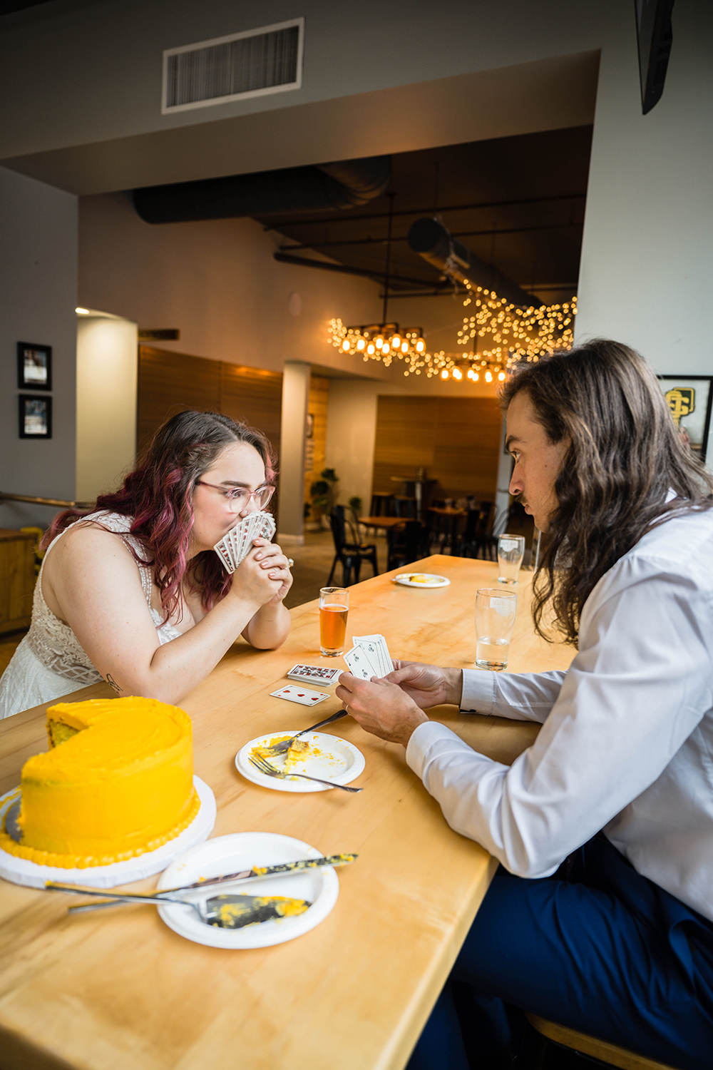 A couple on their elopement day sit at a table at Olde Salem Brewing Company in Downtown Roanoke and play a game of rummy.