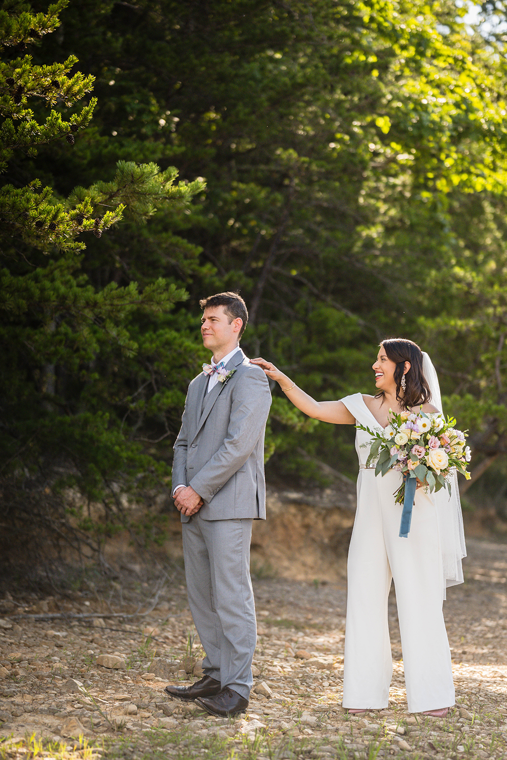 A bride holding her bouquet goes to tap her groom's shoulder during their first look at Carvin's Cove in Roanoke, Virginia on their elopement day.