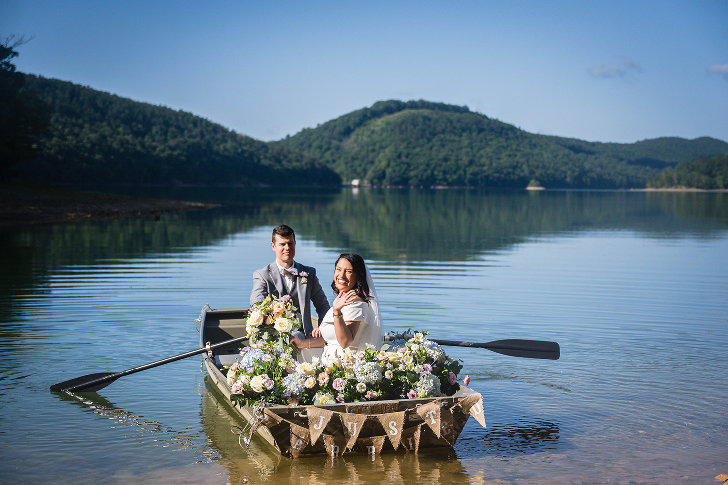 A couple rides out in a rowboat adorned with flowers and a "just married" sign in Carvin's Cove on their elopement day in Roanoke, Virginia.