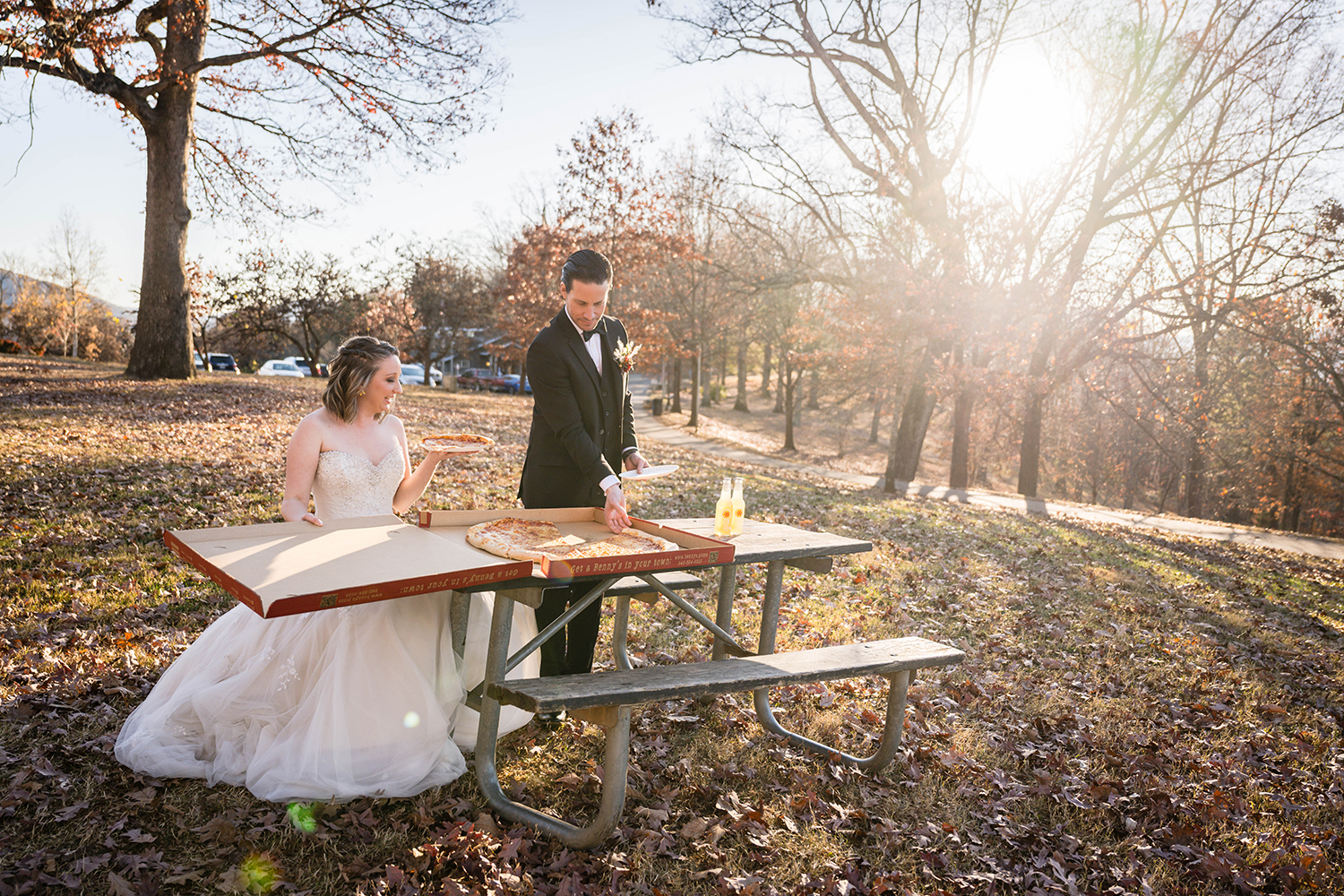 A couple sits at a picnic table at Mill Mountain Park and opens a large pizza from Benny Marconi's to enjoy on their elopement day.