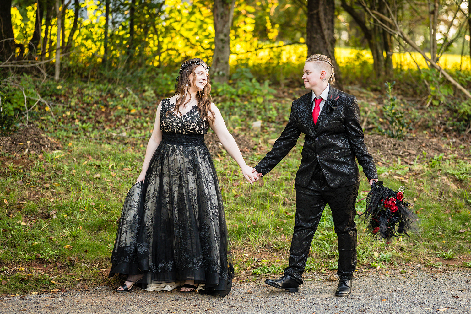 An LGBTQ+ couple on their elopement day walk hand-in-hand down a gravel driveway outside of their Airbnb in Roanoke, Virginia.