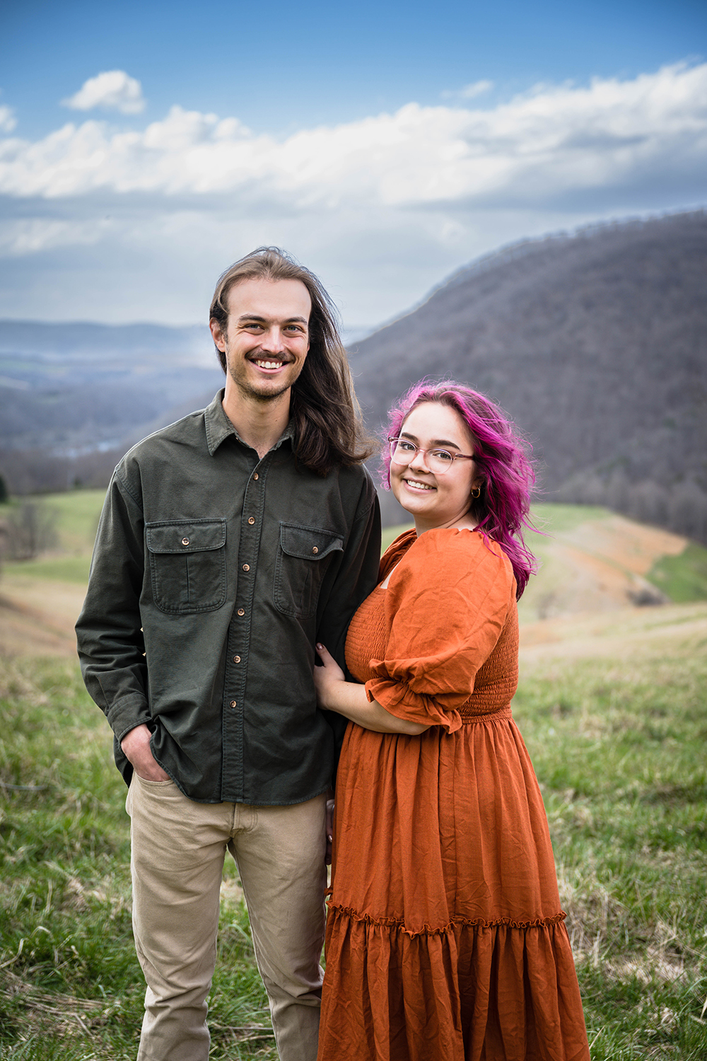 A couple wraps their arms around one another and smiles for a photo during their anniversary adventure session at Hidden Hills in Giles County, Virginia.