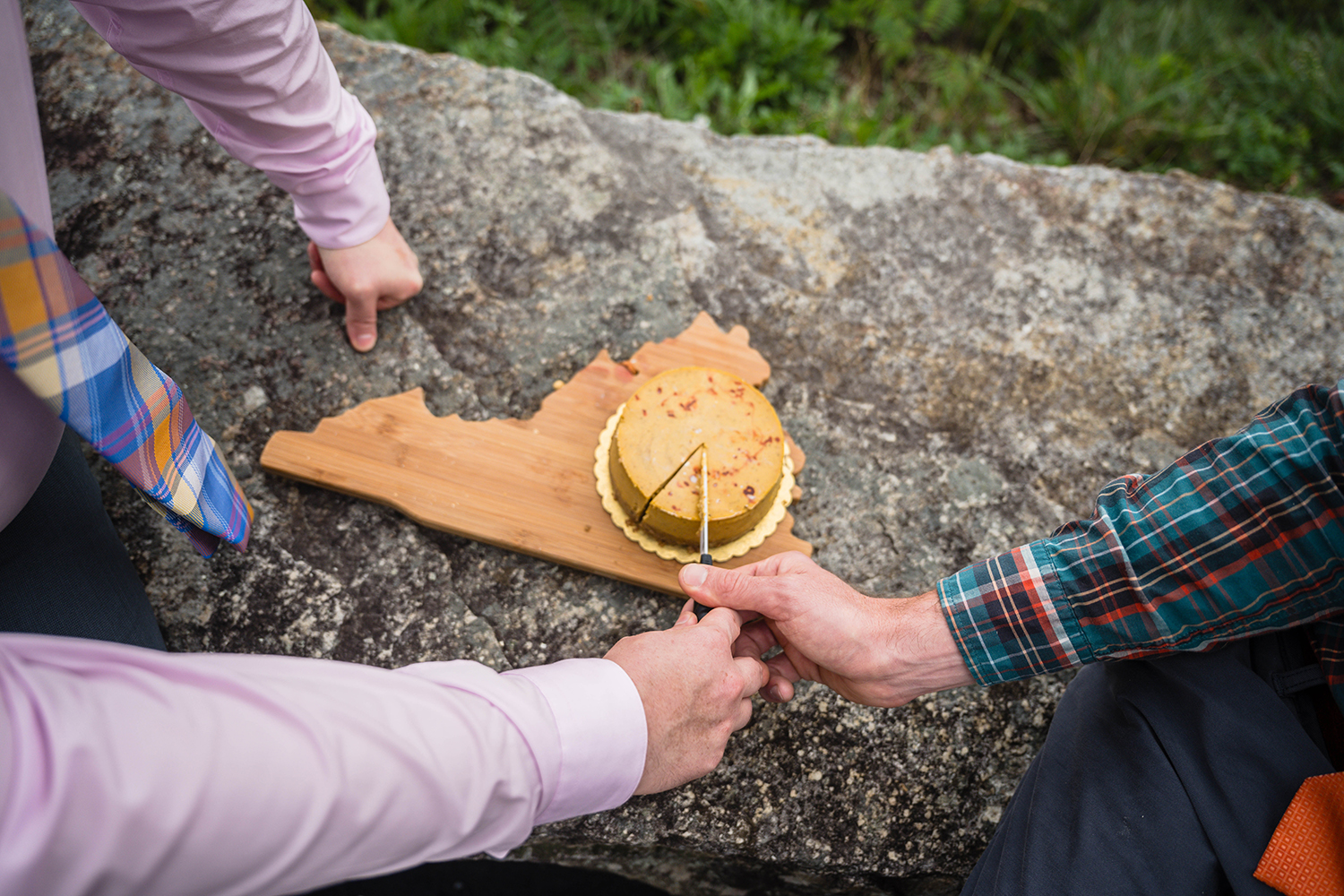 Two queer marriers cut their pumpkin cheesecake together atop of a Virginia state shaped charcuterie board at Loft Mountain Overlook in Shenandoah National Park.