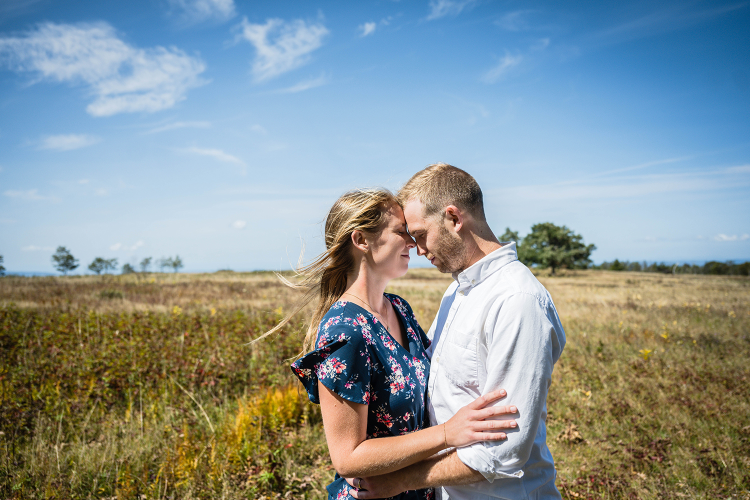 A couple holds onto one another and touch foreheads as they close their eyes and feel the air around them at Big Meadows in Shenandoah National Park.