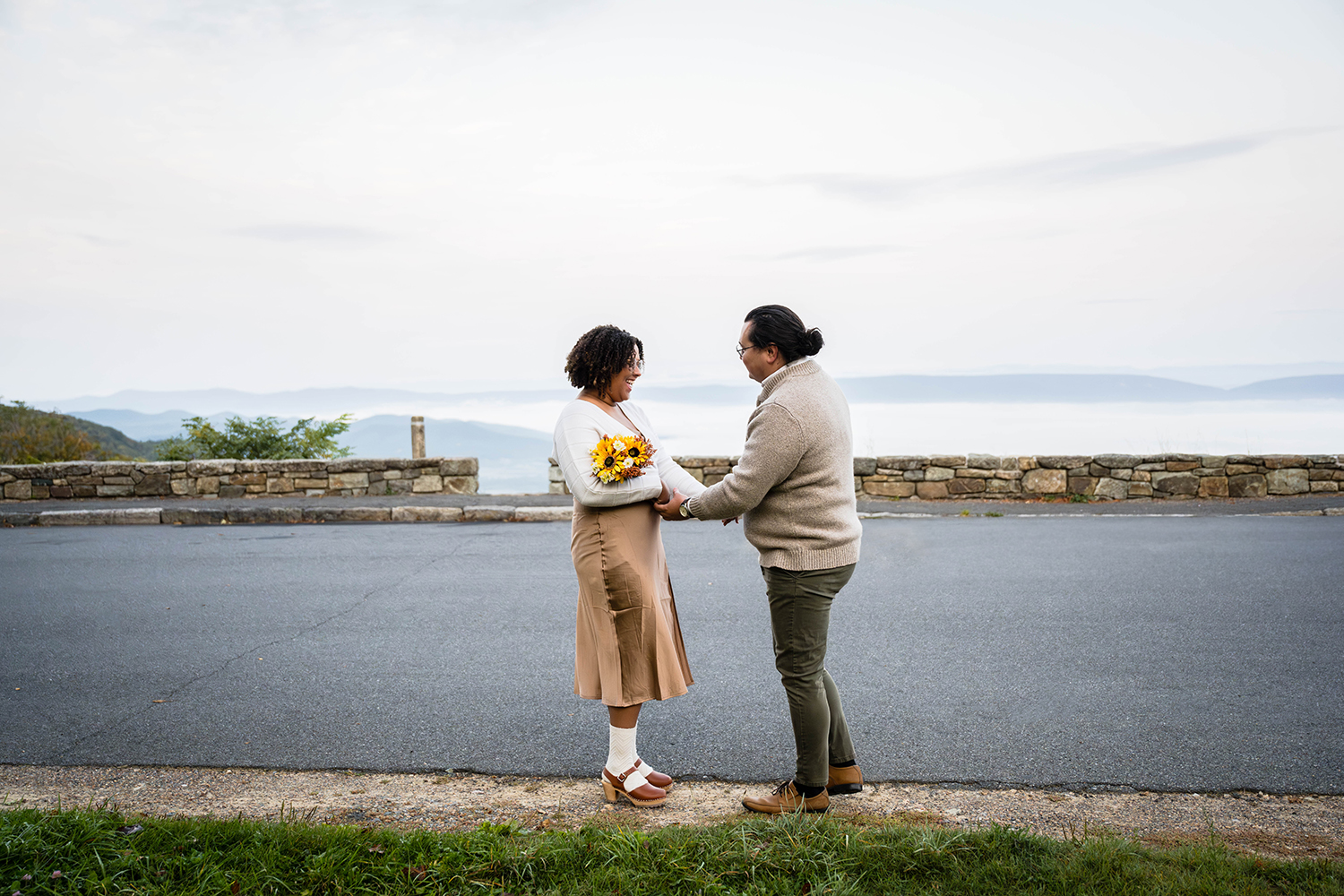 A couple on their elopement day smile widely at one another as they do their first look at Timber Hollow Overlook in Shenandoah National Park. 