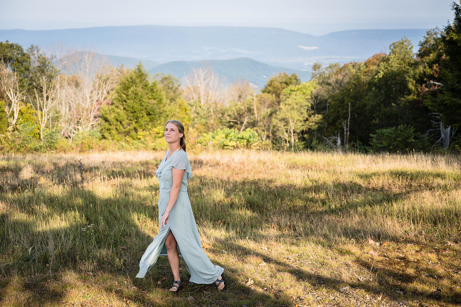 A bride holds onto her dress as she spins back and forth while in a field at Tanner's Ridge Overlook in Shenandoah National Park. 