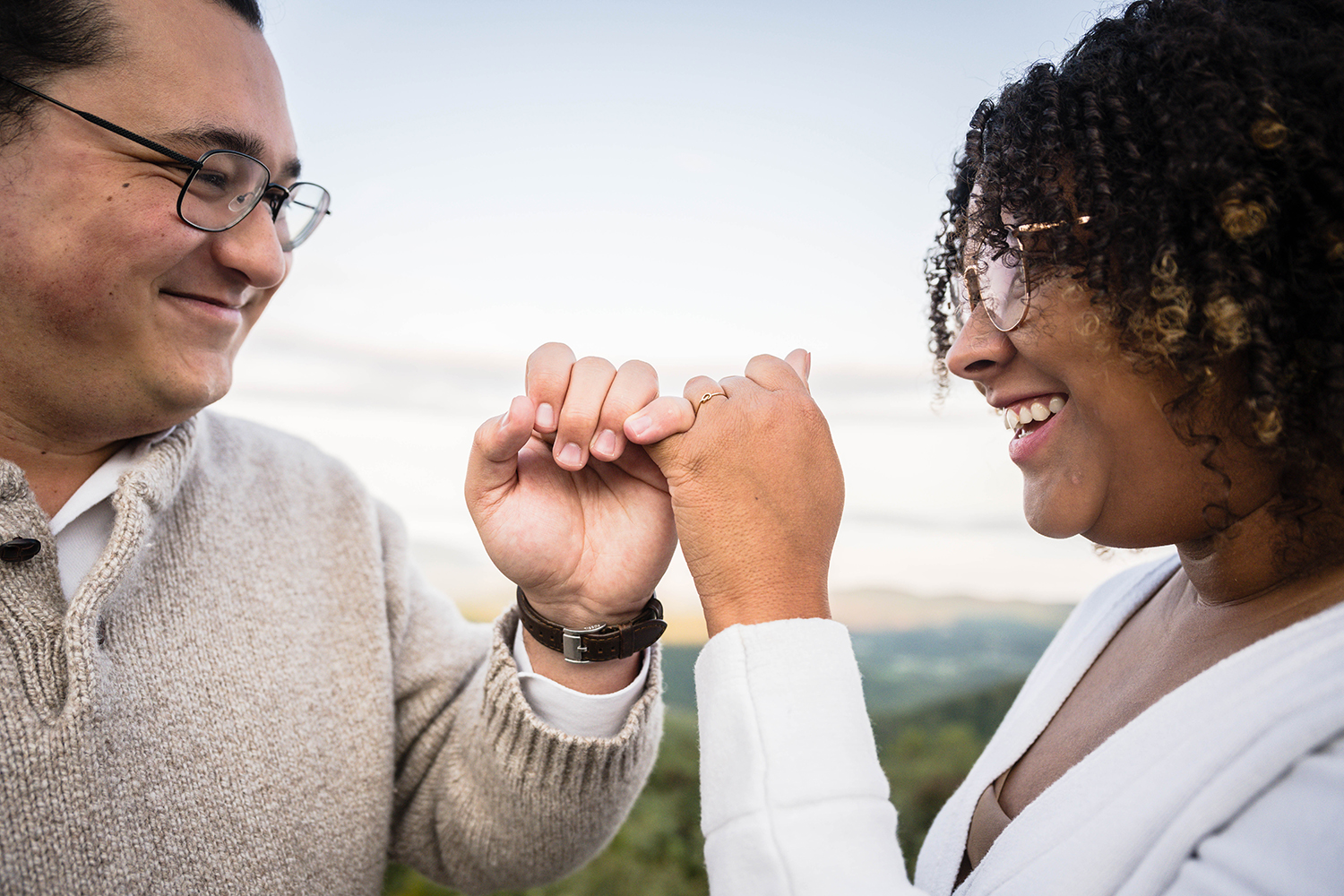 A couple smiles at one another as they make a "pinky promise" during their ceremony at Timber Hollow Overlook in Shenandoah National Park.