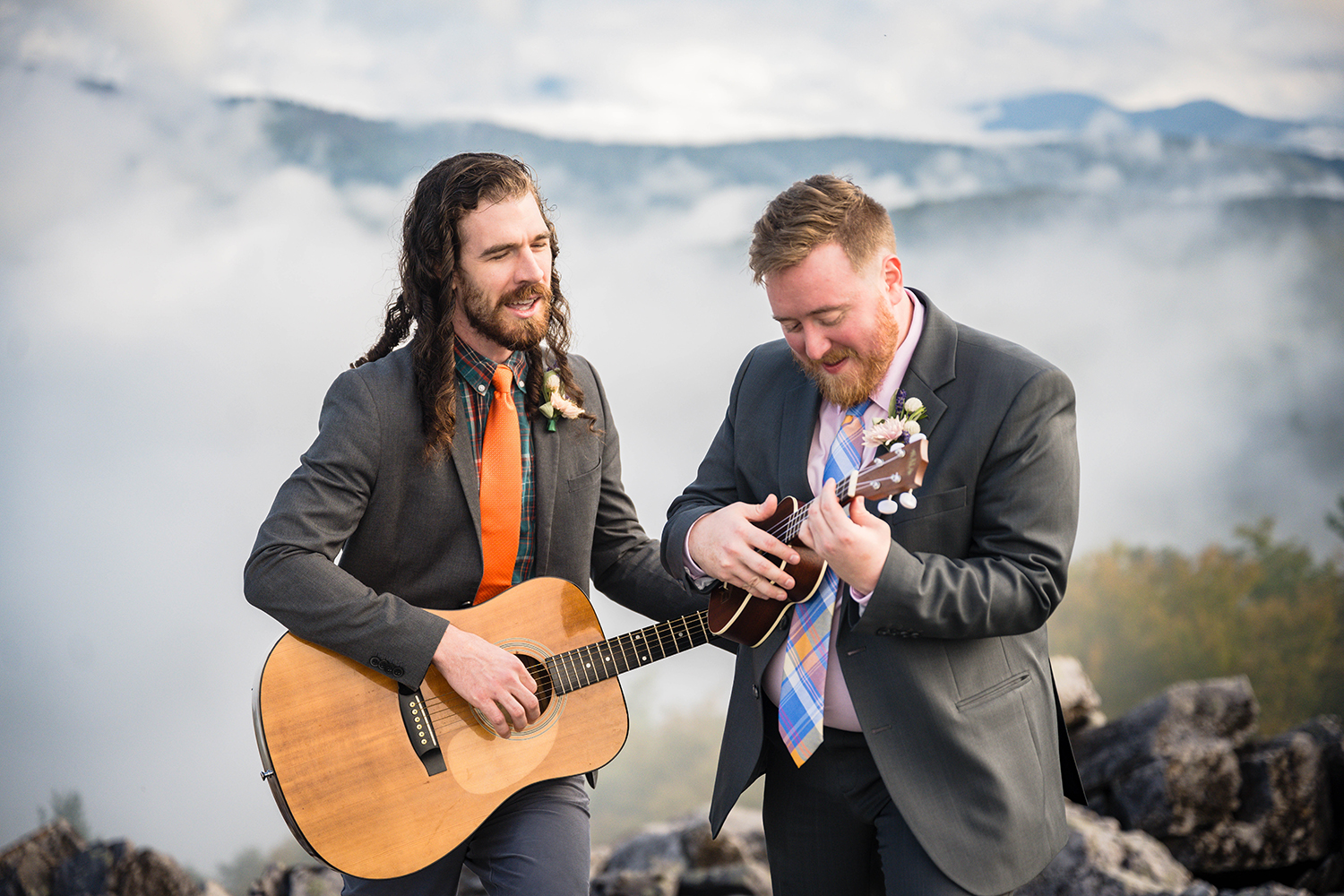 A queer couple play their instruments atop of Blackrock Summit with the Blue Ridge Mountains slightly covered by fog and clouds in the background on their elopement day.