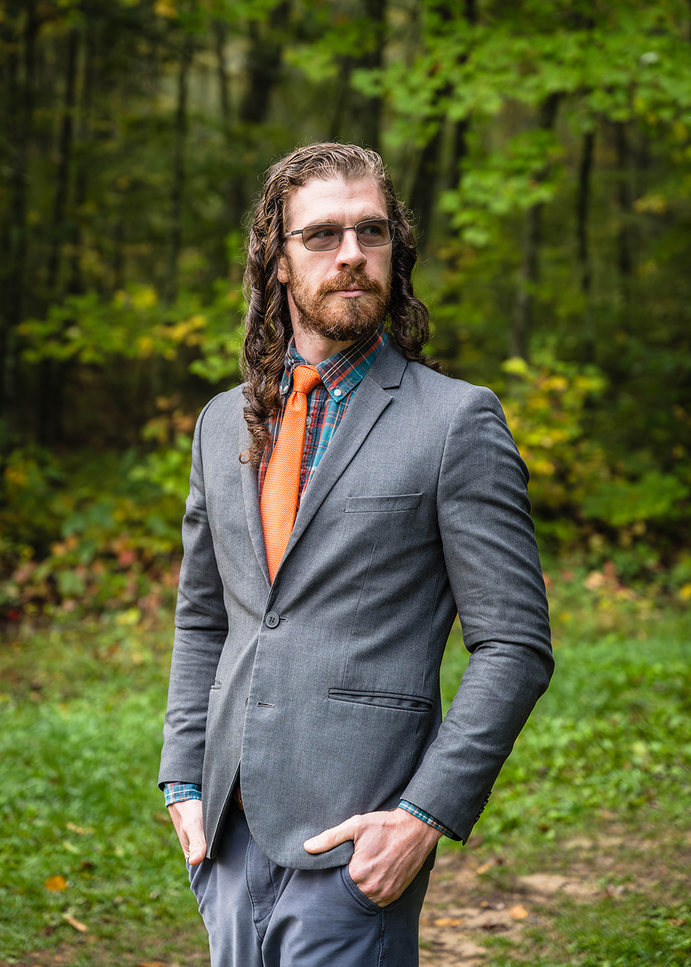 An LGBTQ+ marrier looks off in the distance and keeps a serious expression on their face while standing for a photo.