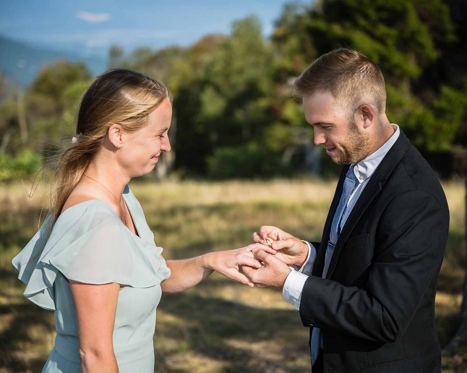 A groom slides a ring onto a bride's finger during their ceremony at Tanner's Ridge Overlook in Shenandoah National Park.