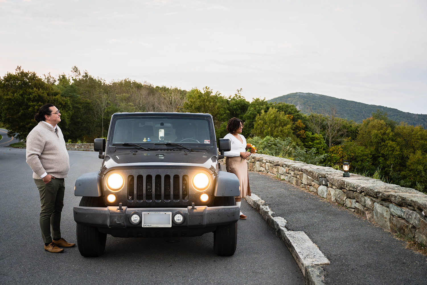 A couple on their elopement day stand on opposite sides of their Jeep to admire the sunrise at Timber Hollow Overlook in Shenandoah National Park. 