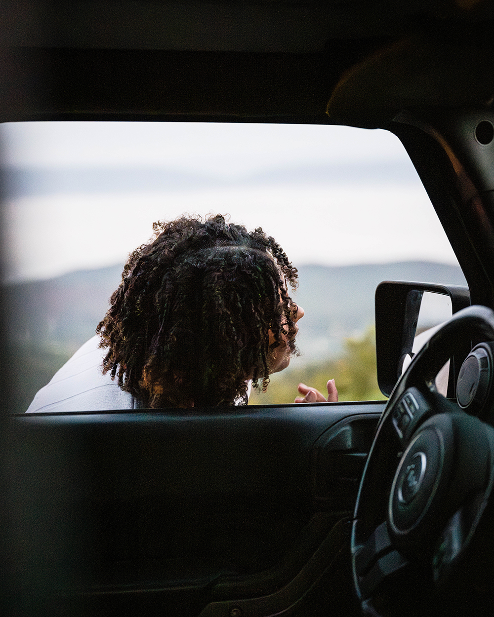 A marrier uses the window of her Jeep to adjust her hair on the morning of their elopement day. 