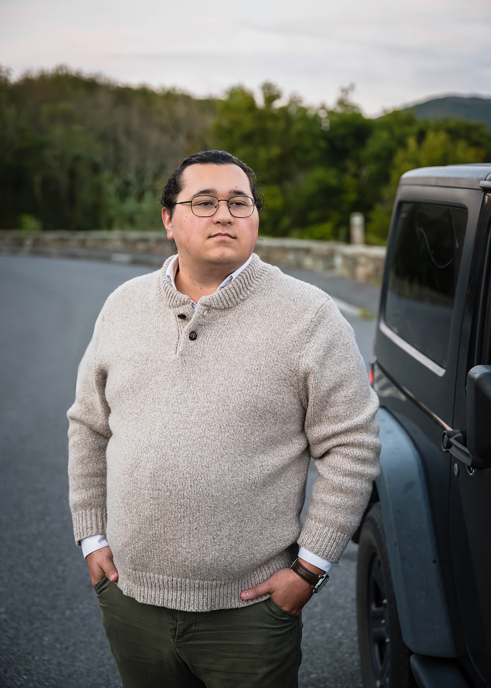 A marrier stands on one side of a Jeep to pose for a photo.