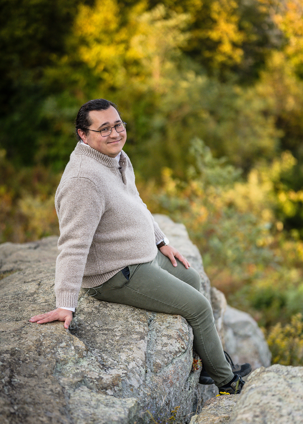 A marrier sits on the edge of a rock and smiles at the camera for a photo.