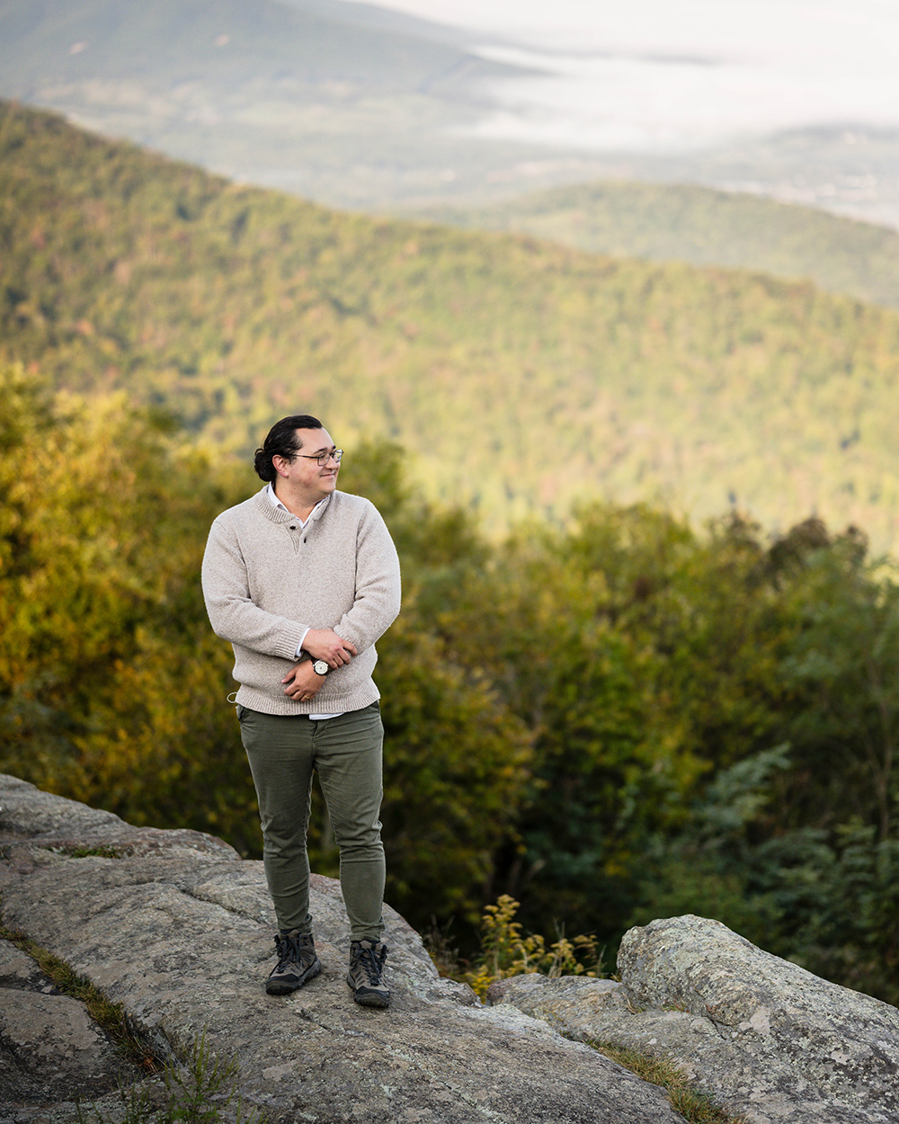 A marrier on their wedding day stands on a large rock at Timber Hollow Overlook and looks out at the mountain views.