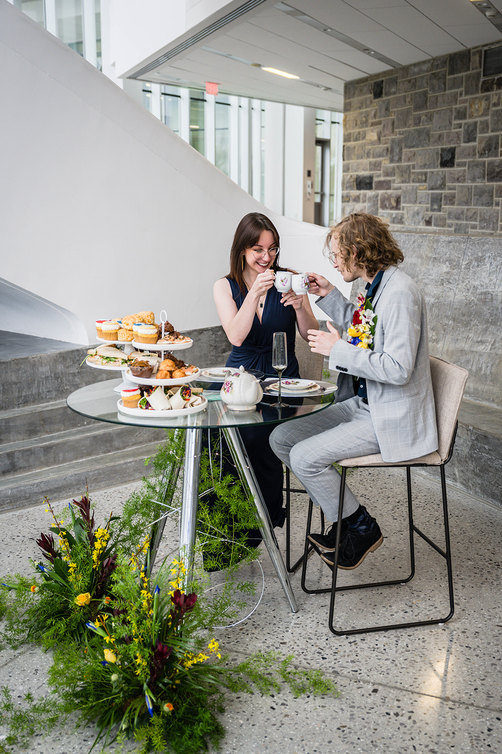 A man and woman enjoy a meal together at a table, sharing food and conversation in a cozy setting. They're seated inside the Virginia Tech Moss Arts Center for their elopement.