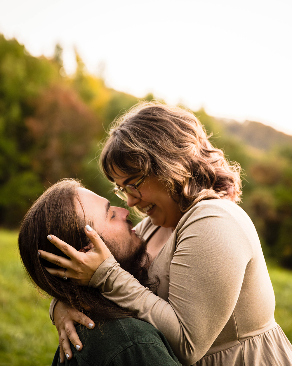 A man holds his partner up and looks at her while she holds onto him. The pair smile widely at one another.