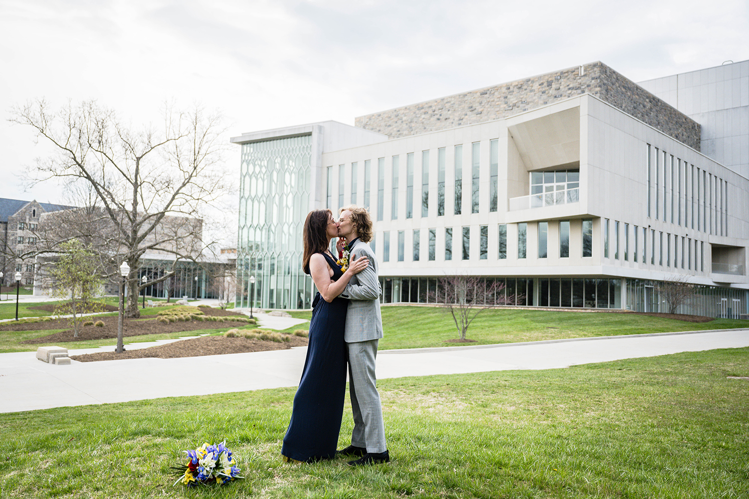 A couple shares a romantic kiss in front of the Virginia Tech Moss Arts Center on their elopement day, capturing a moment of love and affection.